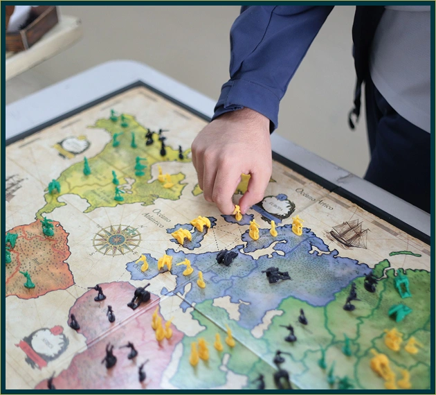 Dichtbij opname van een hand die kleine gele plastic soldaatjes op een landkaart van een strategisch bordspel plaatst